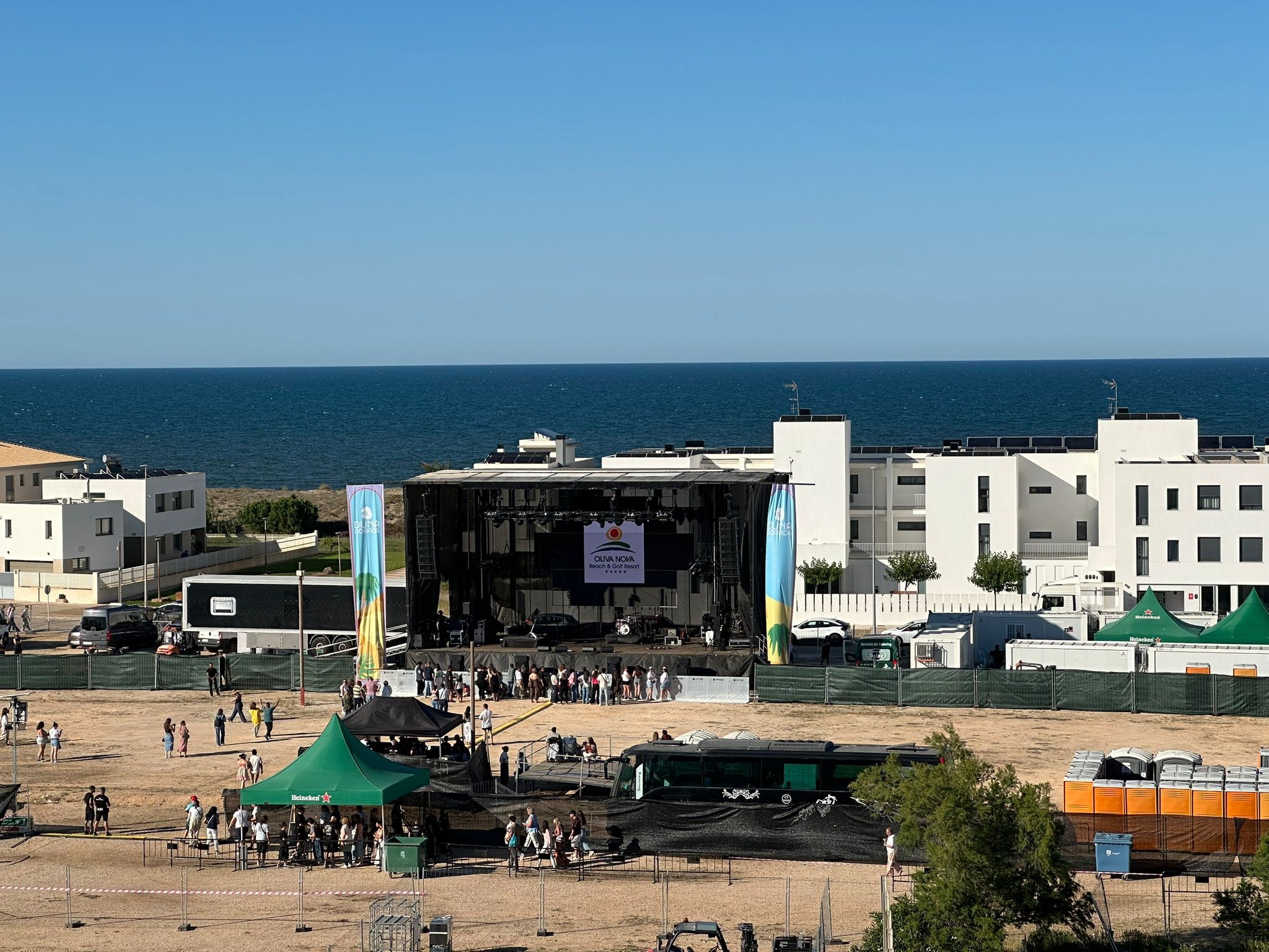 Escenario del Festival Duna Dorada durante el día, con bloques residenciales y de apartamentos al fondo