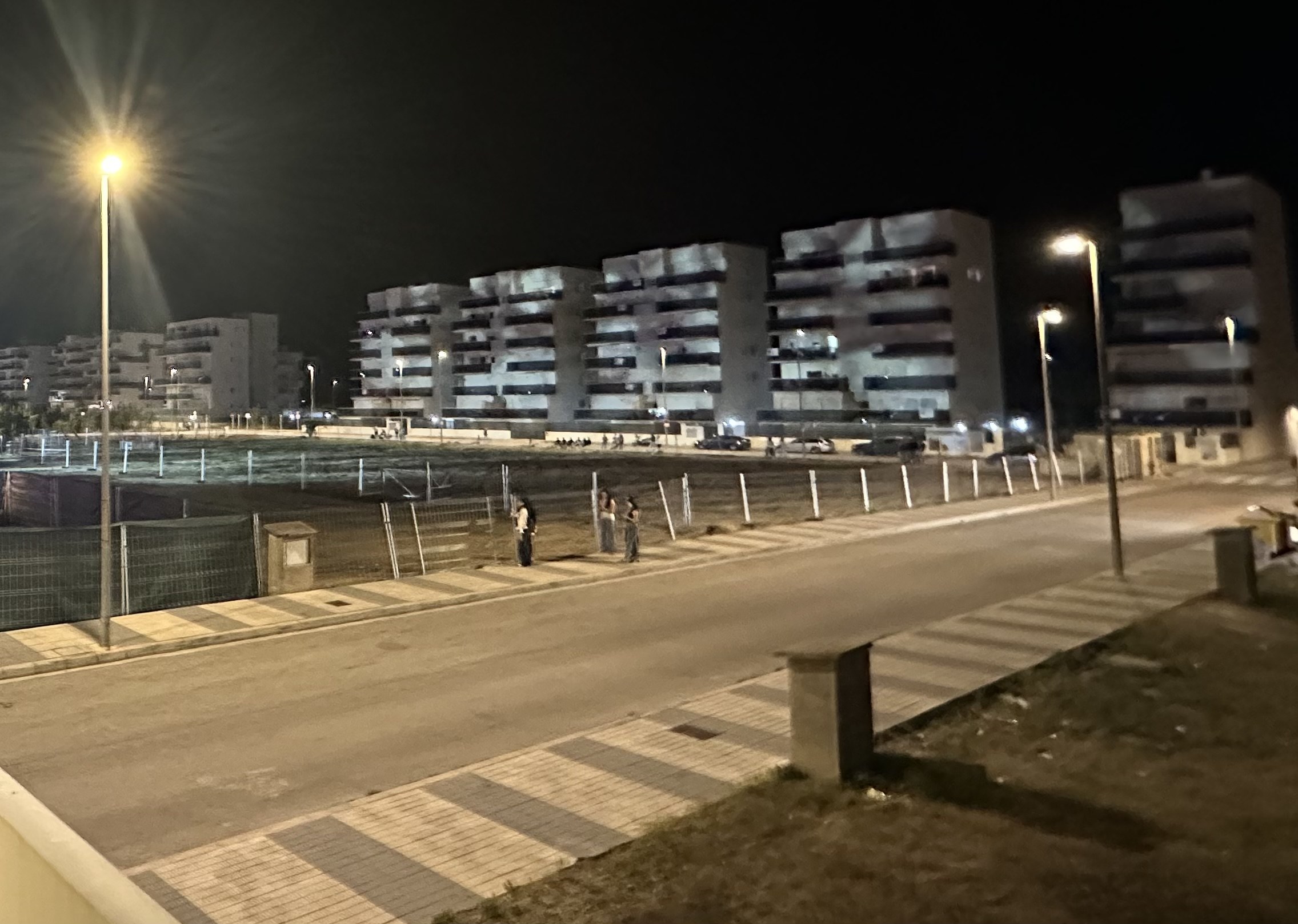 Bloques residenciales de la Avinguda dels Llauradors completamente iluminados por los focos del Festival Duna Dorada en plena noche